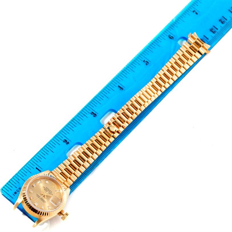 The Rolex President 69178 Women's Yellow Gold Champagne Dial 69178 Women's Yellow Gold Champagne Dial model watch is shown from a top-down angle, revealing the face and linked bracelet along with a measuring ruler.