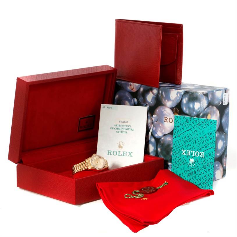 The image shows a Rolex President 69268 Women's Yellow Gold Champagne Dial 69268 Women's Yellow Gold Champagne Dial watch with its red box, booklets, and accessories at a slight angle.