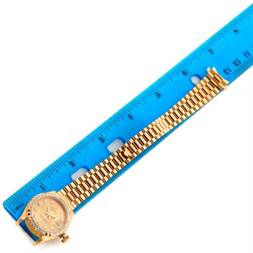 This image shows a Rolex President 69268 Women's Yellow Gold Champagne Dial 69268 Women's Yellow Gold Champagne Dial model watch with a gold bracelet and bezel, placed adjacent to a blue ruler for size reference.