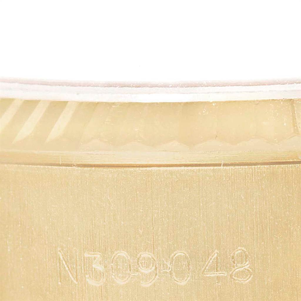 This close-up image of a Rolex President 69178 Women
s Yellow Gold Champagne Dial 69178 Women
s Yellow Gold Champagne Dial watch shows a portion of its gold case and a serial number.