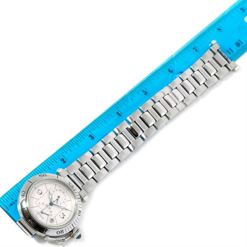 The Pasha model by Cartier is shown from a top-down angle, featuring the face, bezel, and bracelet, aligned next to a ruler.