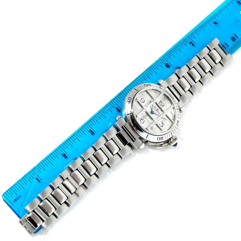 The Cartier Pasha W31059H3 Men
s Stainless Steel Silver Dial W31059H3 Men
s Stainless Steel Silver Dial watch is shown from a top-down angle with a focus on the face and stainless steel bracelet next to a blue ruler.