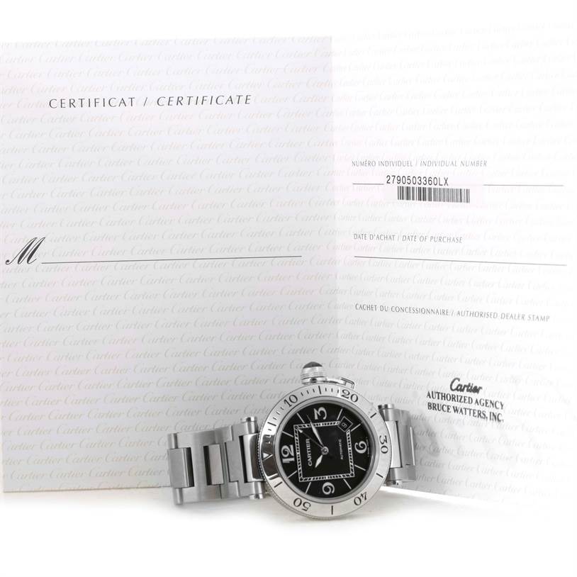 The image shows a Cartier Pasha W31077M7 Men's Stainless Steel Black Dial W31077M7 Men's Stainless Steel Black Dial watch and its open certificate placed behind it.