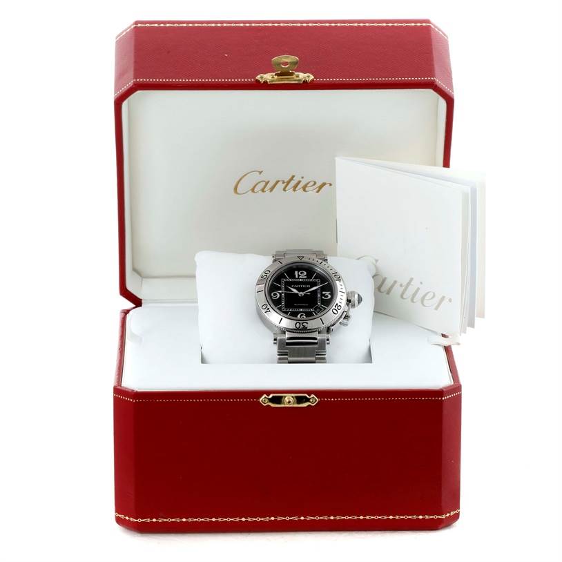 The Cartier Pasha W31077M7 Men
s Stainless Steel Black Dial W31077M7 Men
s Stainless Steel Black Dial watch is shown in a frontal angle inside its red case, accompanied by booklets.