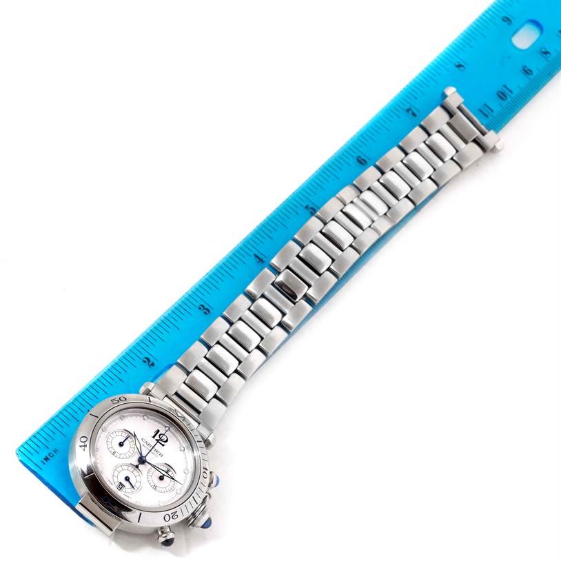 The Cartier Pasha W31030H3 Men's Stainless Steel Silver Dial W31030H3 Men's Stainless Steel Silver Dial watch is shown at a top-down angle, displaying its face, bracelet, and part of a blue ruler.
