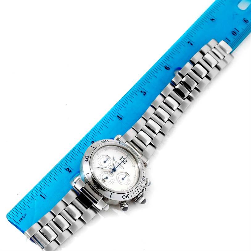 The Cartier Pasha W31030H3 Men
s Stainless Steel Silver Dial W31030H3 Men
s Stainless Steel Silver Dial model watch is shown from an overhead angle, displaying its face, bezel, and bracelet alongside a blue ruler.