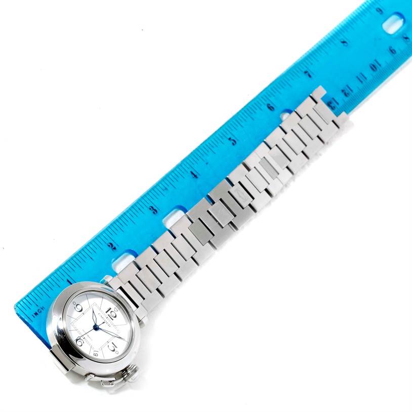 The image shows a Cartier Pasha W31074M7 Men's Stainless Steel White Dial W31074M7 Men's Stainless Steel White Dial watch with a metal bracelet, positioned alongside a blue ruler.
