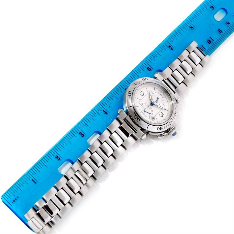 The Cartier Pasha W31037H3 Men's Stainless Steel Silver Dial W31037H3 Men's Stainless Steel Silver Dial watch is shown from a top-down angle alongside a ruler, displaying its face and metal bracelet.