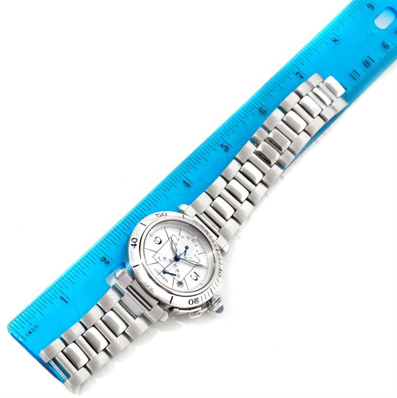 This image shows a top-down view of the Pasha model by Cartier, featuring its face and bracelet beside a blue ruler.