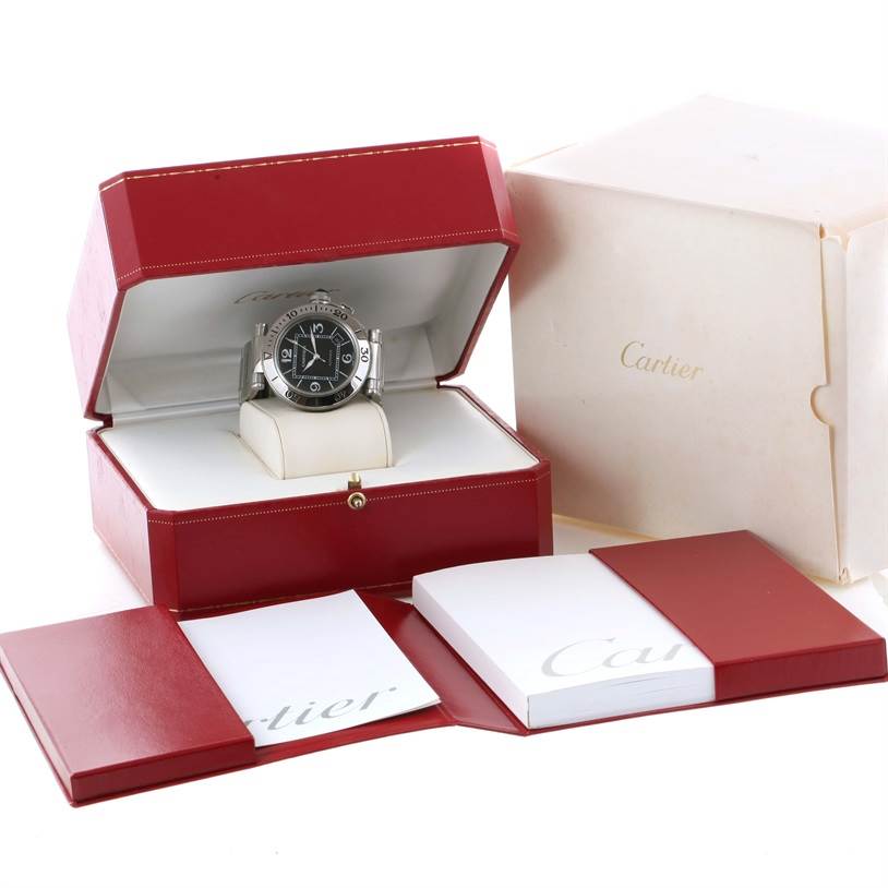 The image shows a Cartier Pasha W31077M7 Men's Stainless Steel Black Dial W31077M7 Men's Stainless Steel Black Dial watch at a frontal angle, placed in an open red box, with additional packaging and booklets.