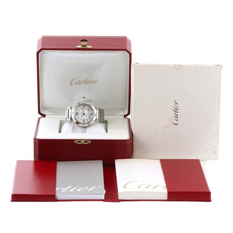 The Cartier Pasha W31080M7 Men's Stainless Steel Silver Dial W31080M7 Men's Stainless Steel Silver Dial watch is shown front-facing inside its open red box, with accompanying packaging and booklets.