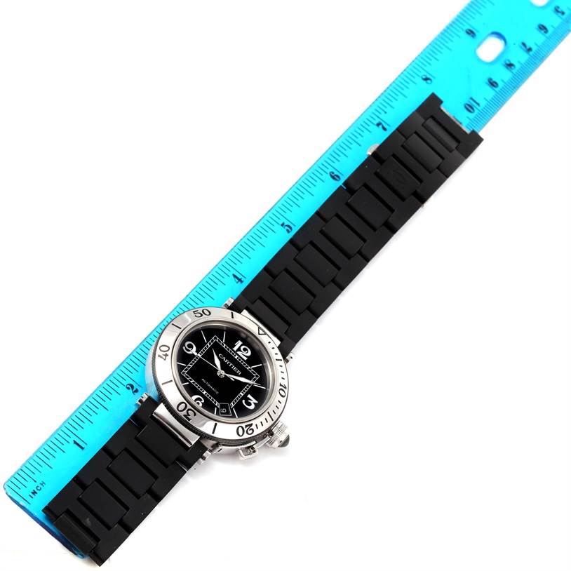 The Cartier Pasha W31077U2 Men's Stainless Steel Black Dial W31077U2 Men's Stainless Steel Black Dial model watch is shown from an overhead angle, with its face, bezel, and strap visible next to a ruler for scale.