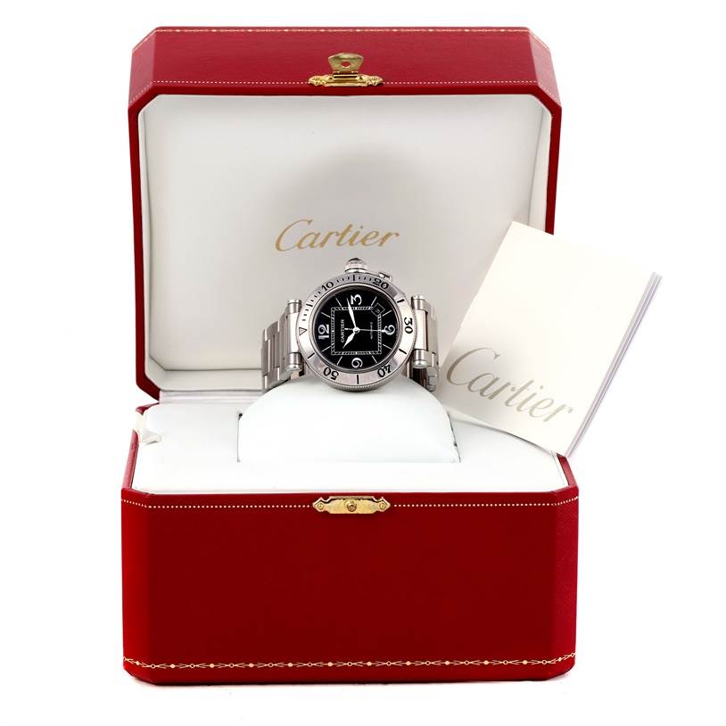 The image shows a Cartier Pasha W31077M7 Men
s Stainless Steel Black Dial W31077M7 Men
s Stainless Steel Black Dial watch in a red open box, displayed front-on alongside its booklet.