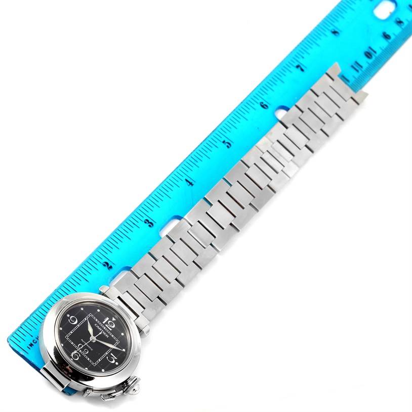 The image shows a Cartier Pasha W31055M7 Men's Stainless Steel Black Dial W31055M7 Men's Stainless Steel Black Dial watch placed next to a ruler, displaying the watch face and metal bracelet.