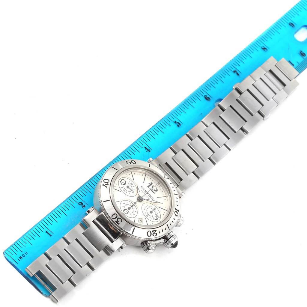 This image shows a Cartier Pasha W31089M7 Men's Stainless Steel Silver Dial W31089M7 Men's Stainless Steel Silver Dial watch laid flat with a blue ruler for scale, displaying the face and bracelet.