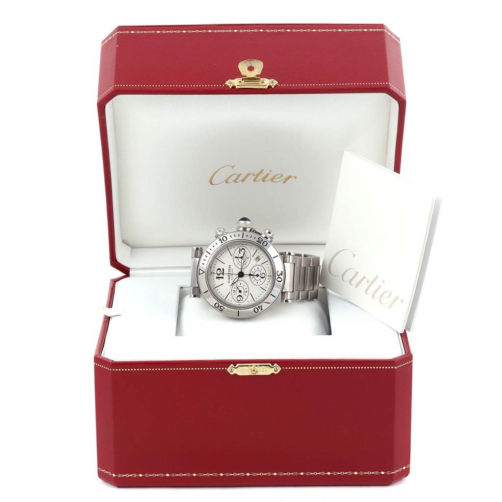 The image shows a Cartier Pasha W31089M7 Men's Stainless Steel Silver Dial W31089M7 Men's Stainless Steel Silver Dial watch displayed front-on inside an open red Cartier box with accompanying documentation.