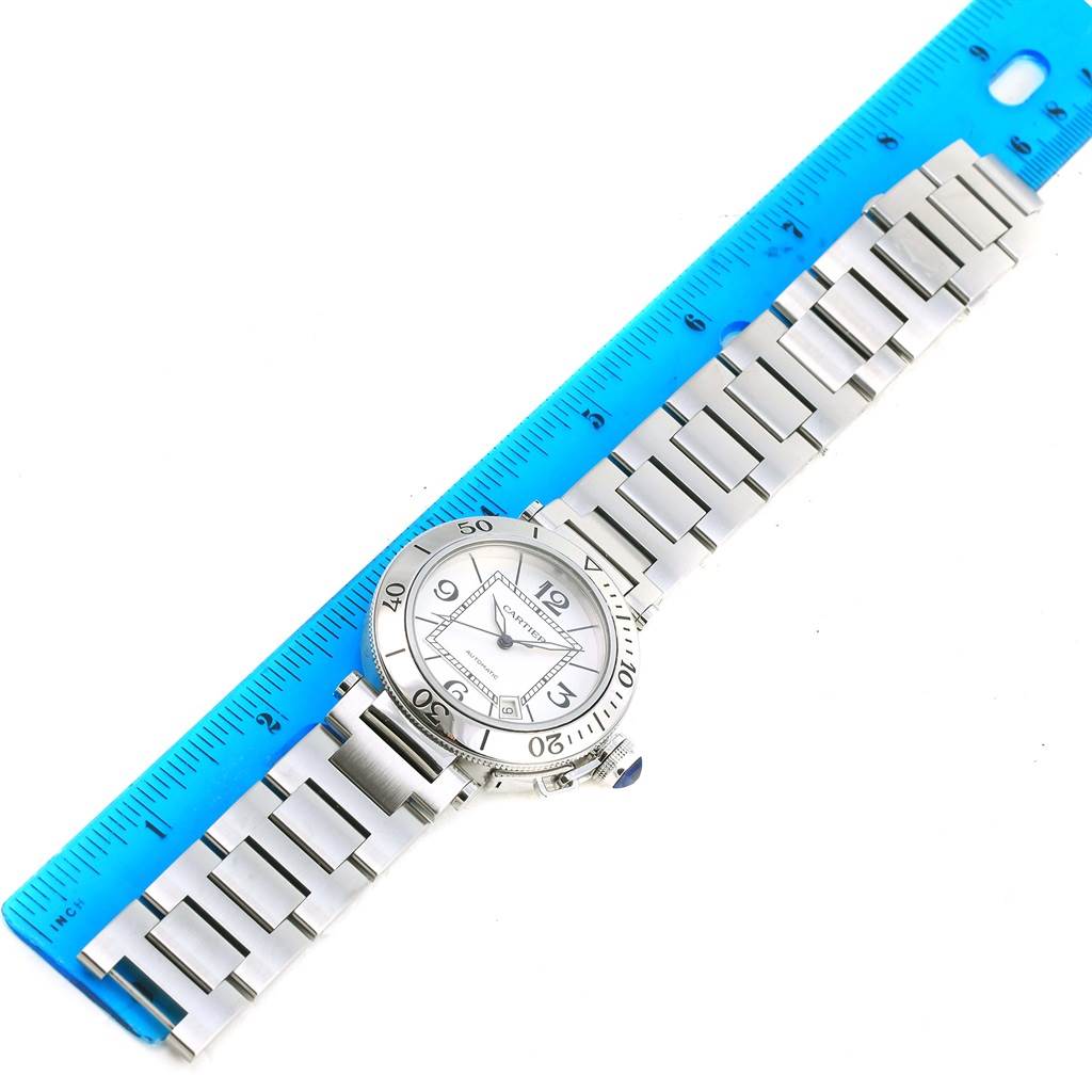 This image shows a Cartier Pasha W31080M7 Men's Stainless Steel Silver Dial W31080M7 Men's Stainless Steel Silver Dial watch with a metal strap, positioned alongside a blue ruler for scale.