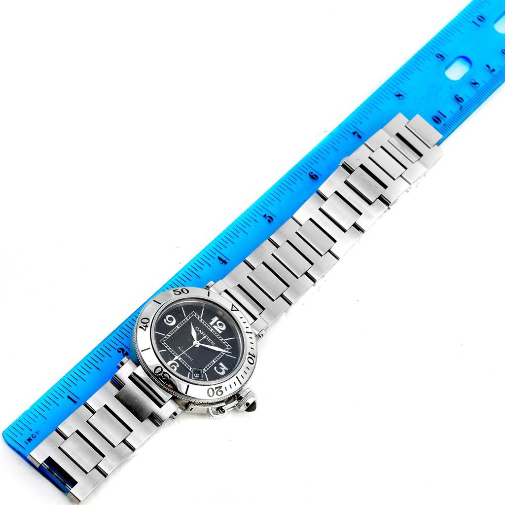 This image shows a Cartier Pasha W31077M7 Men
s Stainless Steel Black Dial W31077M7 Men
s Stainless Steel Black Dial watch laid flat next to a blue ruler for measuring.