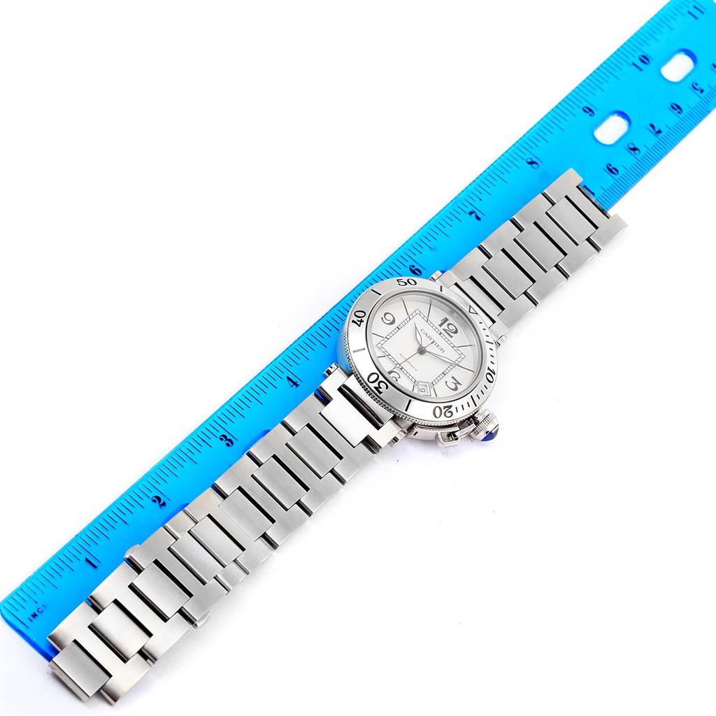 The Cartier Pasha W31080M7 Men
s Stainless Steel Silver Dial W31080M7 Men
s Stainless Steel Silver Dial watch is shown flat with its face, band, and a blue ruler for measurement.