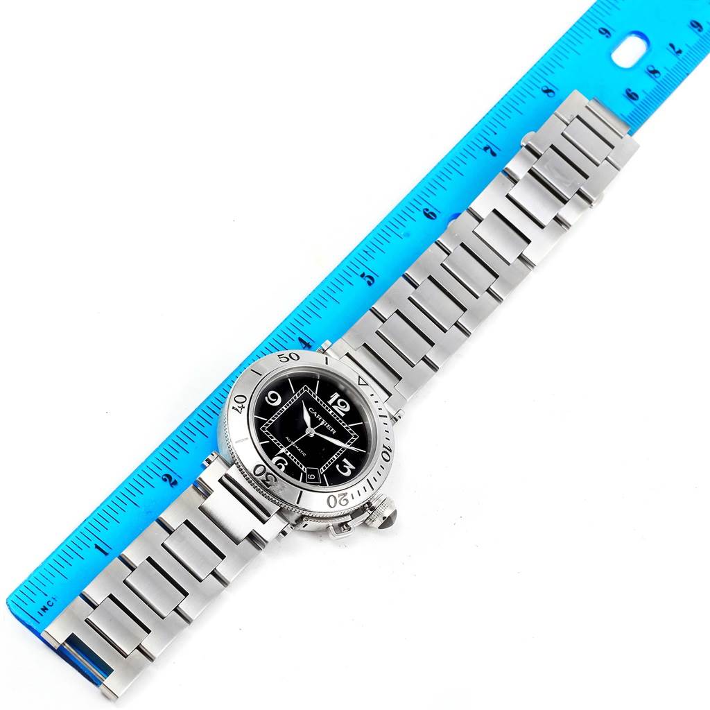 The Cartier Pasha W31077M7 Men's Stainless Steel Black Dial W31077M7 Men's Stainless Steel Black Dial watch is displayed flat, showing its face, bezel, bracelet, and a ruler for scale.