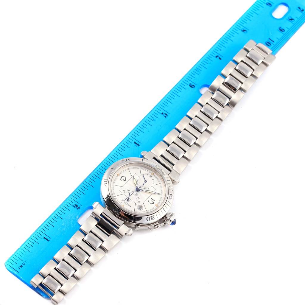 The Cartier Pasha W31037H3 Men's Stainless Steel Silver Dial W31037H3 Men's Stainless Steel Silver Dial watch is shown lying flat with its metallic band extended alongside a blue ruler for scale.