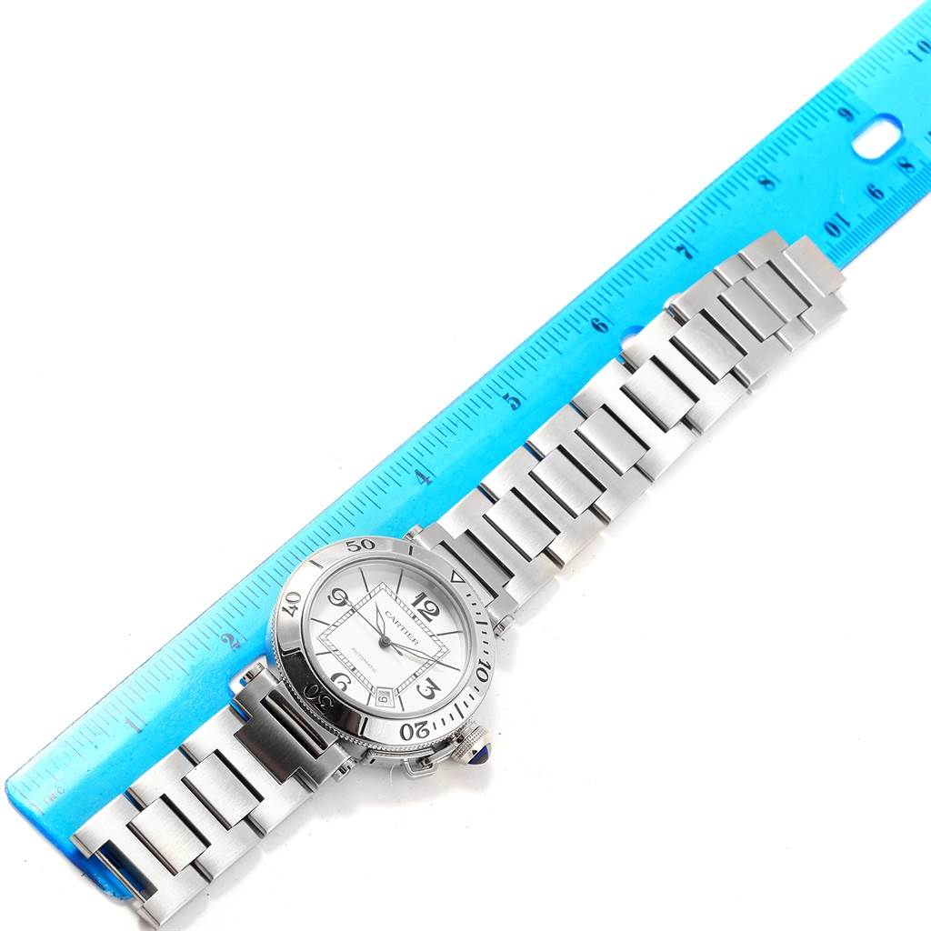 The image shows a Cartier Pasha W31080M7 Men's Stainless Steel Silver Dial W31080M7 Men's Stainless Steel Silver Dial watch laid flat with its band extended, next to a blue ruler for scale.