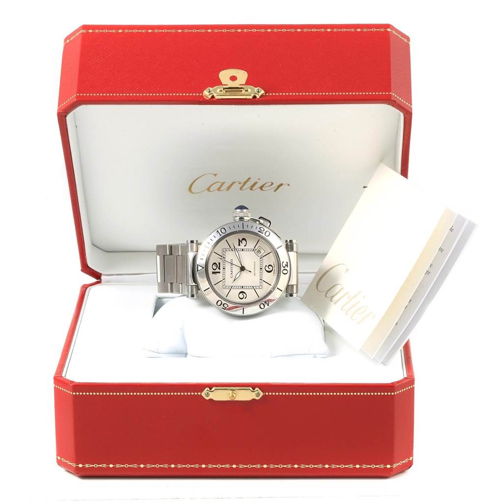 The Cartier Pasha W31080M7 Men's Stainless Steel Silver Dial W31080M7 Men's Stainless Steel Silver Dial watch is displayed front-on in an open red Cartier box, with accompanying documentation on the right.
