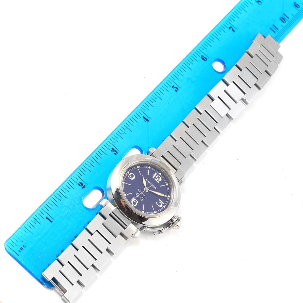 The image shows a top-down view of a Cartier Pasha W31047M7 Men
s Stainless Steel Blue Dial W31047M7 Men
s Stainless Steel Blue Dial watch, including its face, bezel, and metal bracelet, with a ruler for scale.