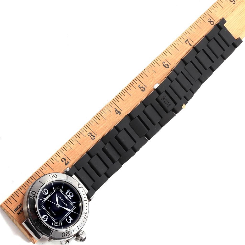 This image shows the Cartier Pasha W31077U2 Men
s Stainless Steel Black Dial W31077U2 Men
s Stainless Steel Black Dial watch
s face and black rubber strap, alongside a ruler for scale.
