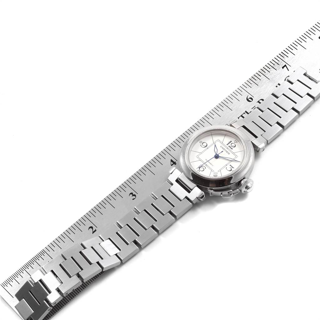 The Cartier Pasha W31074M7 Stainless Steel White Dial W31074M7 Stainless Steel White Dial watch is shown from an overhead angle, highlighting the face and stainless steel bracelet alongside a ruler.