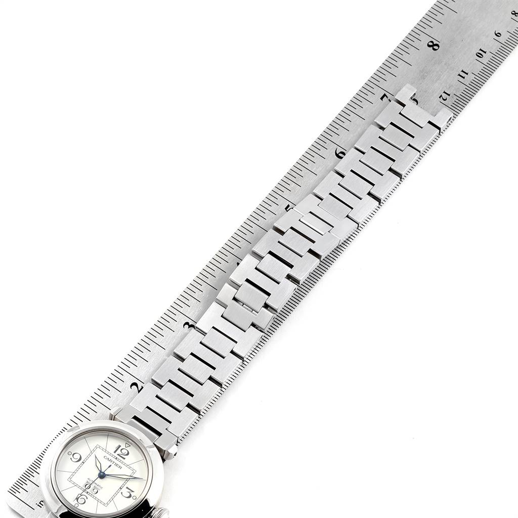 The image shows a Cartier Pasha W31055M7 Men's Stainless Steel White Dial W31055M7 Men's Stainless Steel White Dial watch with the face at the bottom left and a metal band measured against a ruler.