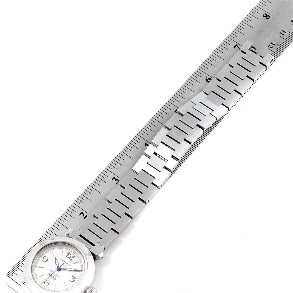 The Cartier Pasha W31044M7 Men's Stainless Steel White Dial W31044M7 Men's Stainless Steel White Dial watch is shown from a top-down angle, displaying its face and stainless steel bracelet with a ruler for scale.