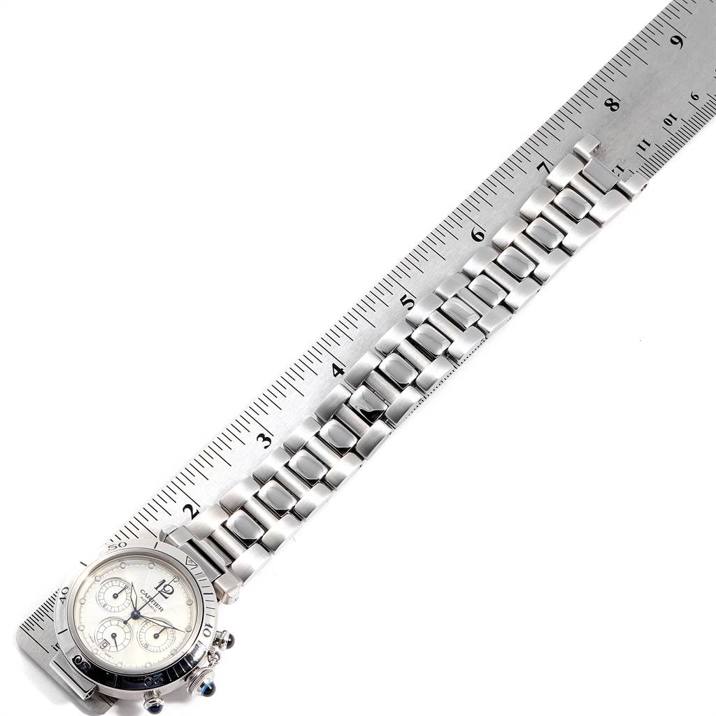 This image shows the Cartier Pasha W31030H3 Men's Stainless Steel Silver Dial W31030H3 Men's Stainless Steel Silver Dial watch laid alongside a ruler, highlighting its metal bracelet and face at an angled top-down view.