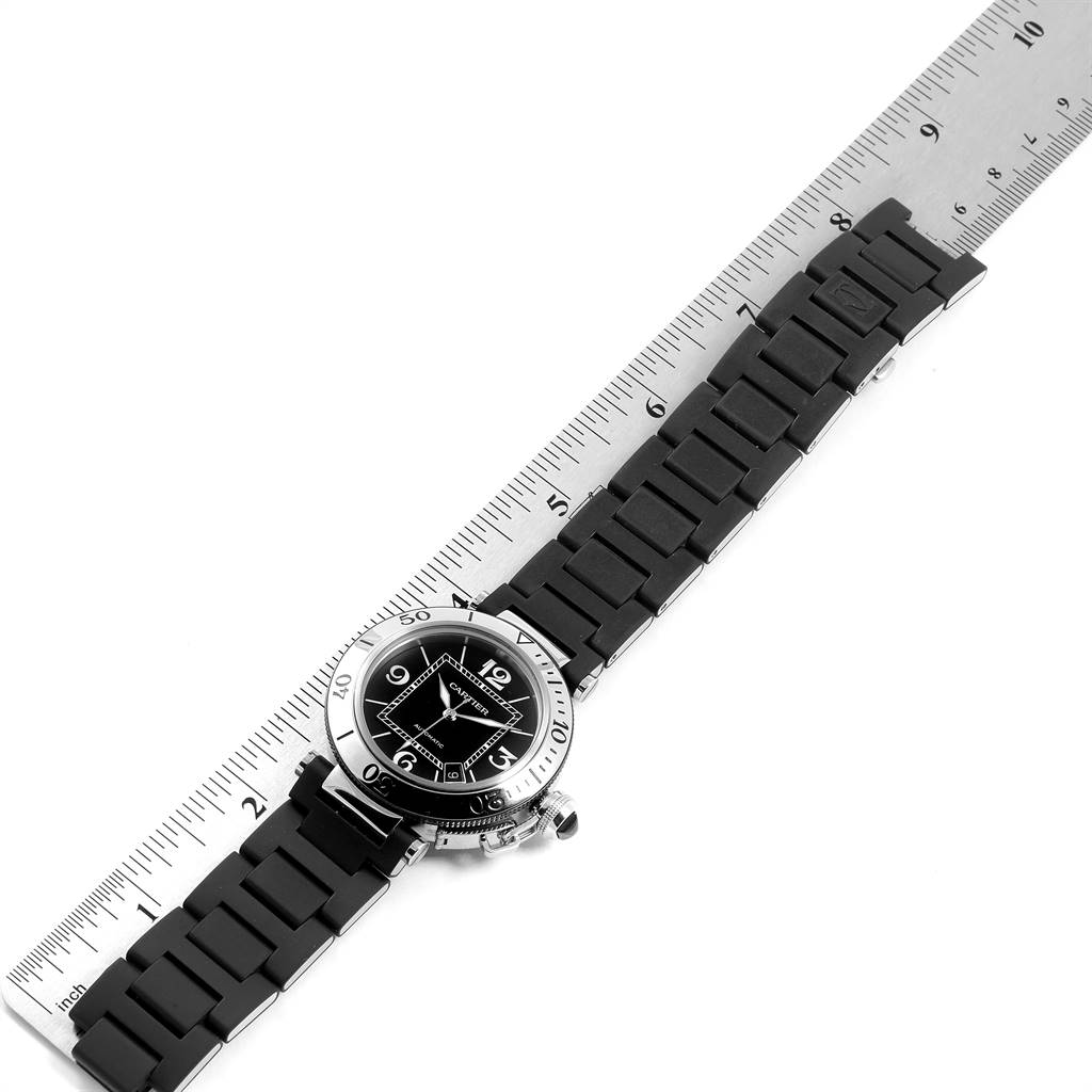 The Cartier Pasha W31077U2 Men's Stainless Steel Black Dial W31077U2 Men's Stainless Steel Black Dial watch is shown from a top-down angle displaying the watch face, bezel, and strap, placed next to a ruler.