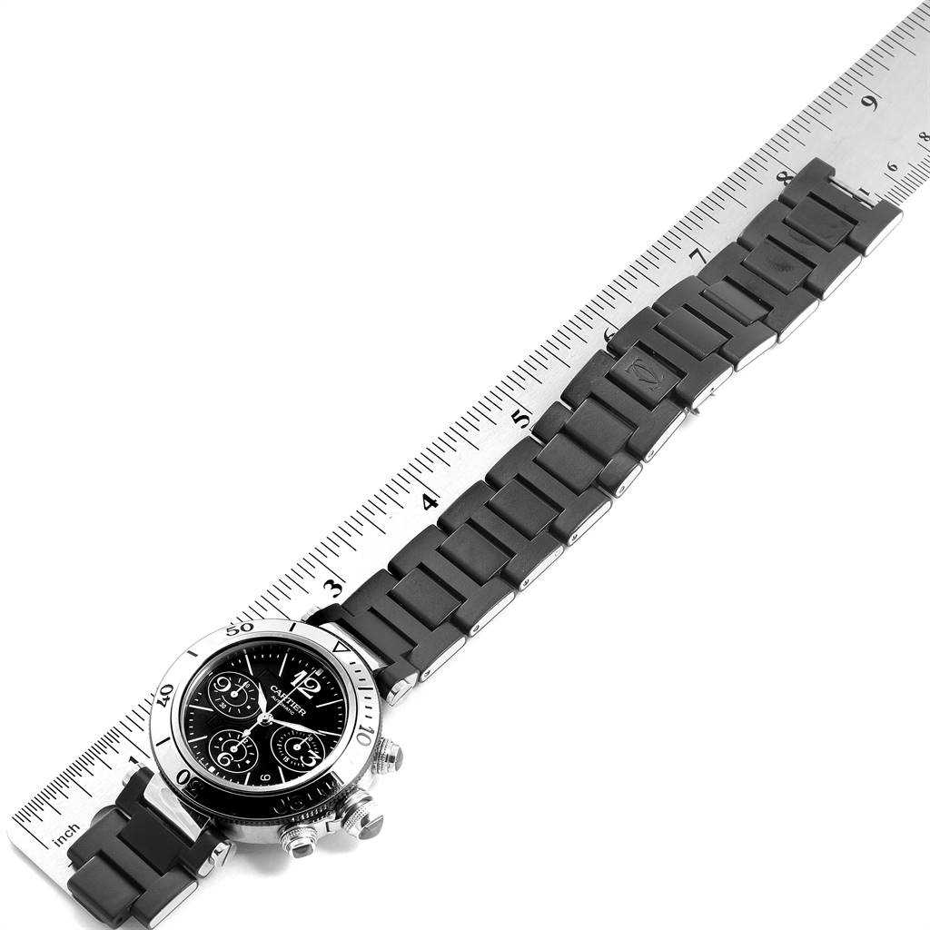 The image shows a Cartier Pasha W31088U2 Men's Stainless Steel Black Dial W31088U2 Men's Stainless Steel Black Dial watch from an angled top view, including the face, bezel, pushers, and bracelet, next to a ruler.