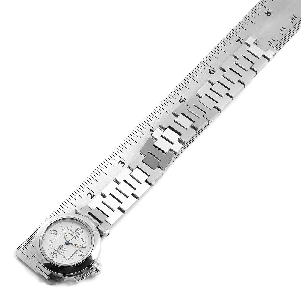 The image shows a Pasha model by Cartier watch laid flat with a metal bracelet next to a ruler for measurement.