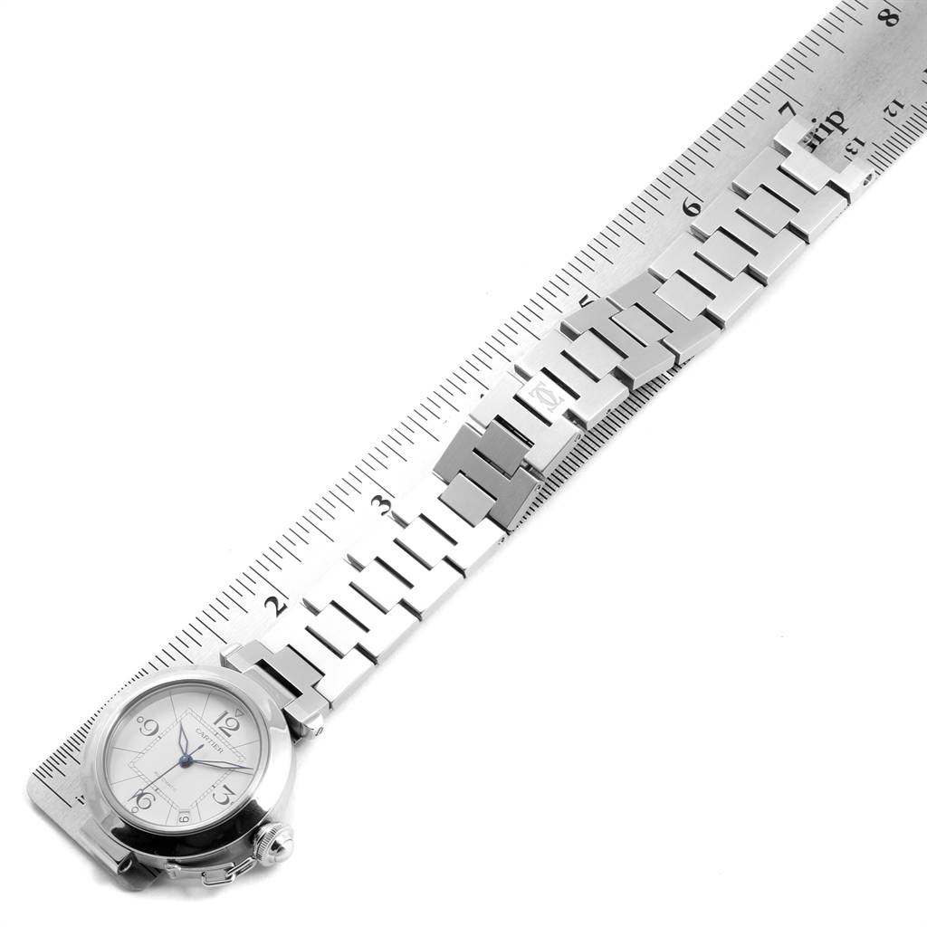The image shows a top-down view of a Cartier Pasha W31074M7 Stainless Steel White Dial W31074M7 Stainless Steel White Dial watch with its band aligned next to a ruler for measurement.