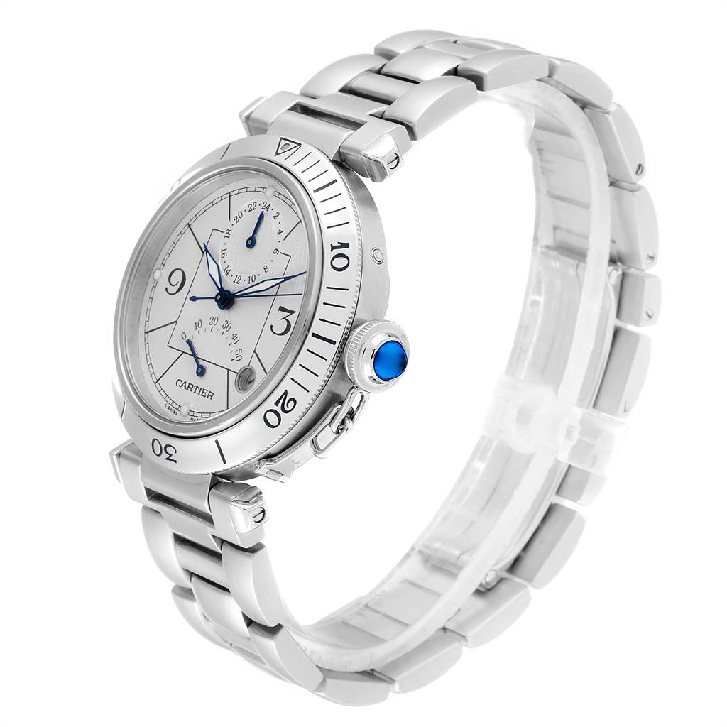 The image shows a Pasha model by Cartier at a slight angle, highlighting its face, bezel, crown with blue cabochon, and metal bracelet.