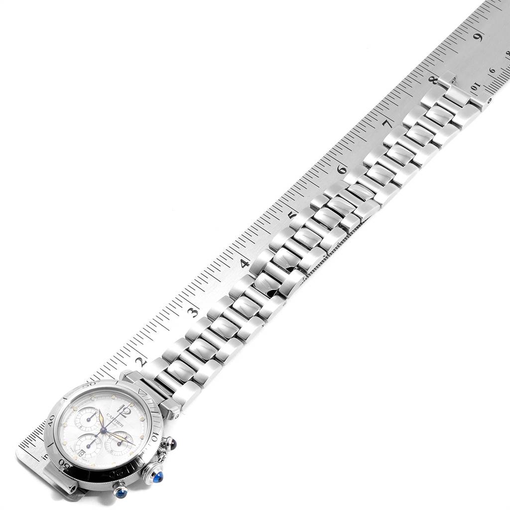 The Cartier Pasha W31030H3 Men's Stainless Steel Silver Dial W31030H3 Men's Stainless Steel Silver Dial watch is shown at an angle demonstrating its face and metal bracelet alongside a ruler for scale.