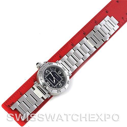 The image shows a Cartier Pasha W31077M7 Men
s Stainless Steel Black Dial W31077M7 Men
s Stainless Steel Black Dial watch placed diagonally on a red ruler, displaying its full band and face.
