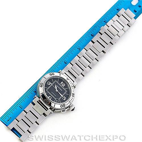 The Cartier Pasha W31077M7 Men's Stainless Steel Black Dial W31077M7 Men's Stainless Steel Black Dial watch is shown at a slight diagonal angle, featuring the dial and a metal bracelet laid next to a blue ruler.