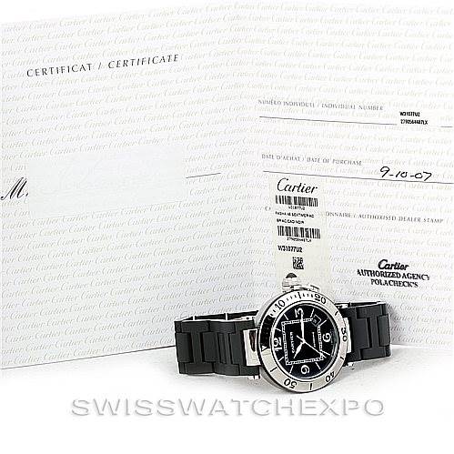 The image shows a Cartier Pasha W31077U2 Men's Stainless Steel Black Dial W31077U2 Men's Stainless Steel Black Dial model watch from a front angle, along with its certification and documentation in the background.