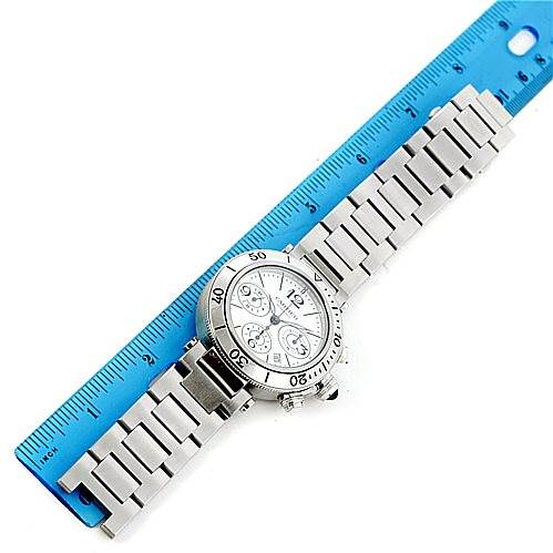 This image shows the Cartier Pasha W31089M7 Men's Stainless Steel Silver Dial W31089M7 Men's Stainless Steel Silver Dial watch laid flat next to a blue ruler, displaying its face and metal bracelet.