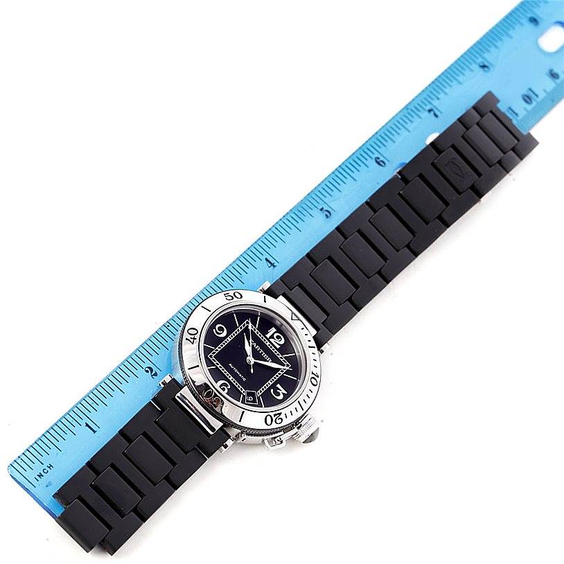 This image shows the face and the bracelet of the Cartier Pasha W31077U2 Men
s Stainless Steel Black Dial W31077U2 Men
s Stainless Steel Black Dial model watch, laid adjacent to a blue ruler to measure its length.