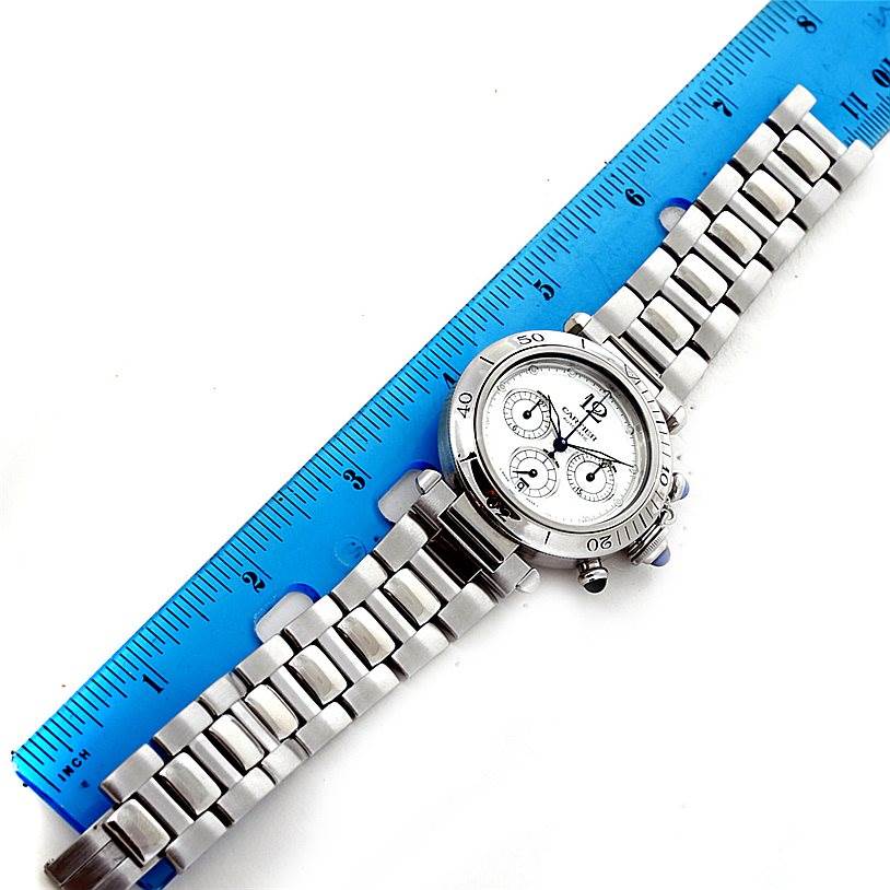 The Cartier Pasha W31030H3 Men's Stainless Steel Silver Dial W31030H3 Men's Stainless Steel Silver Dial watch is shown from a top-down angle with a stainless steel bracelet and a blue ruler for scale.