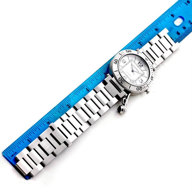 The image shows a top-view angle of a Cartier Pasha W31080M7 Men
s Stainless Steel Silver Dial W31080M7 Men
s Stainless Steel Silver Dial watch with a stainless steel bracelet next to a blue ruler.
