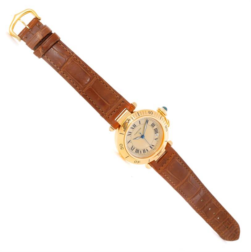 The image shows a Cartier Pasha 10351 Men's Yellow Gold Silver Dial 10351 Men's Yellow Gold Silver Dial watch with a gold case, Roman numeral dial, and a brown leather strap, viewed from above.