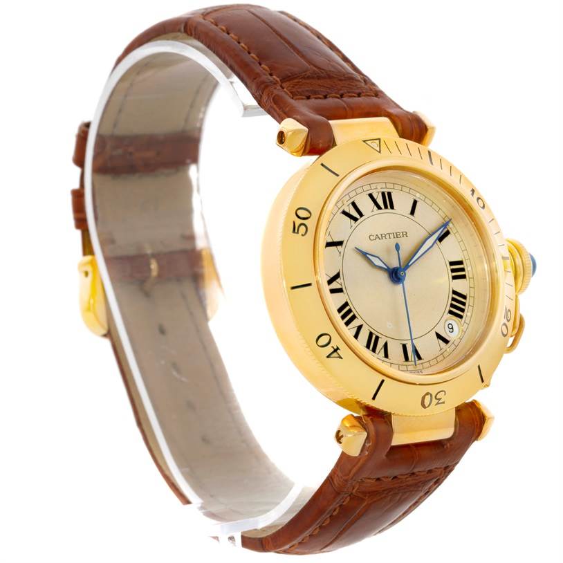 The Pasha by Cartier watch is shown at an angled side view, highlighting its gold case, brown leather strap, and Roman numeral dial.