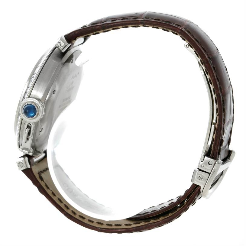 This side view image shows the Pasha model by Cartier, focusing on its case, crown with a blue cabochon, and leather strap.