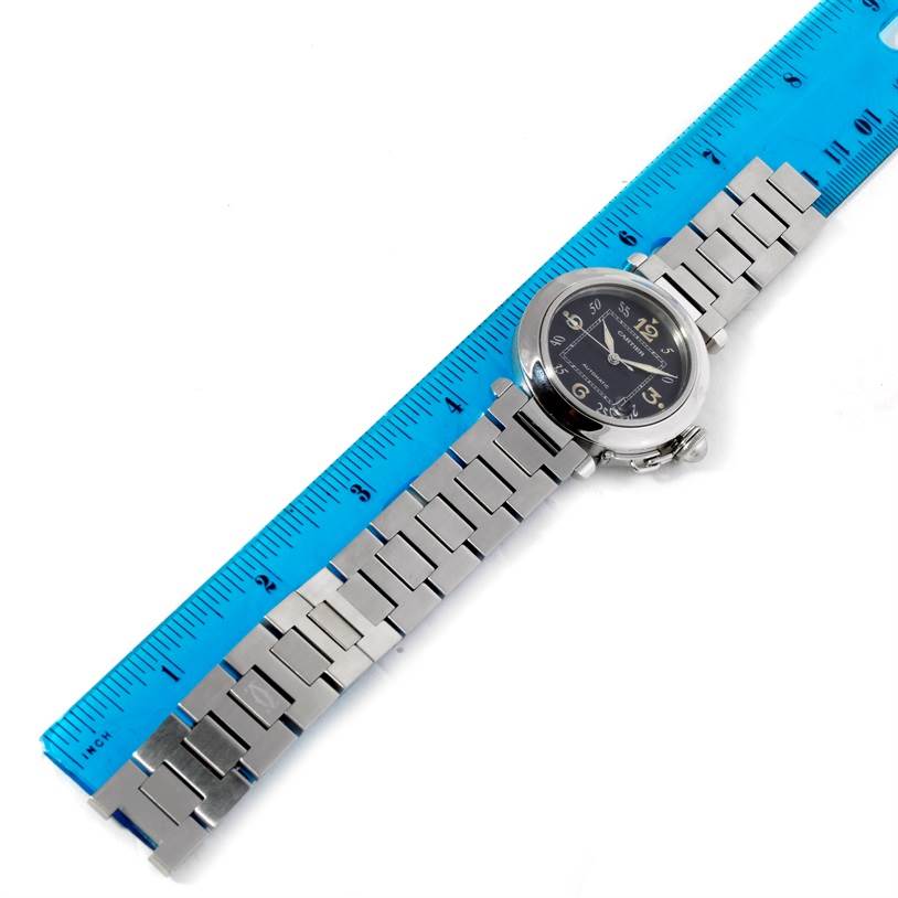 This image shows an overhead view of a Cartier Pasha W31043M7 Stainless Steel Black Dial W31043M7 Stainless Steel Black Dial watch, including its face, bracelet, and deployment clasp, measured against a blue ruler.